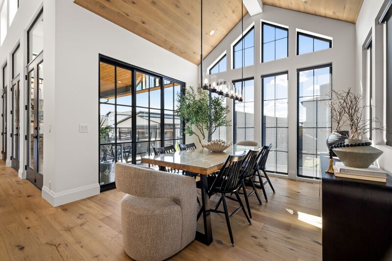 Dining area beneath a vaulted wood ceiling with floor-to-ceiling windows