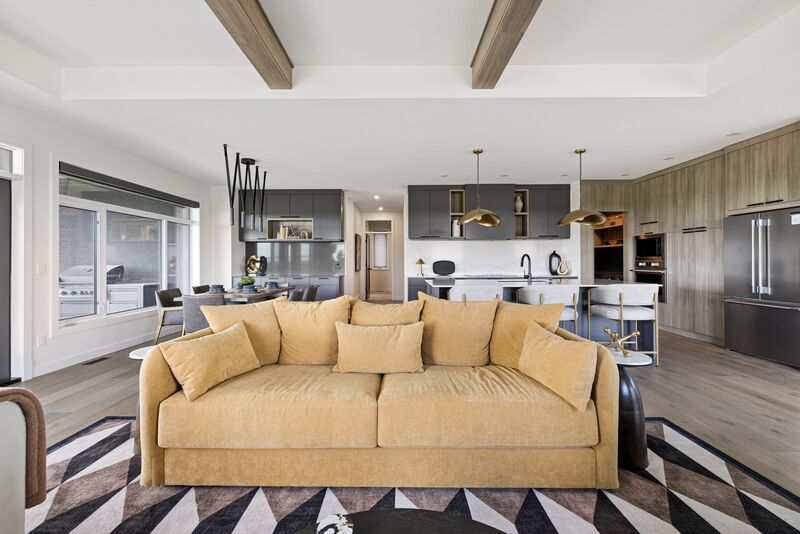 Open-concept great room with beamed ceiling and kitchen beyond